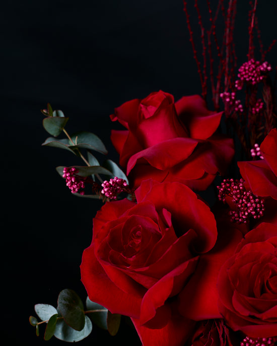 Bouquet of red roses with green leaves on a black background